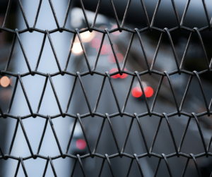 Chain link fence with cars on the highway in the background